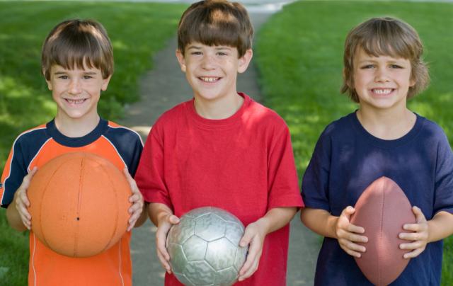 Three boys holding sports balls