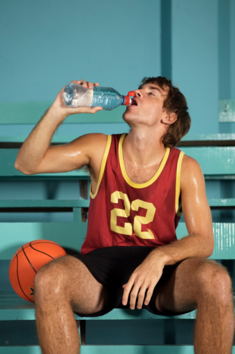 Teenage basketball player hydrating with water bottle