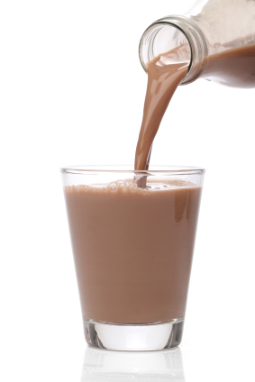 Chocolate milk pouring from bottle to glass