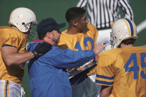Football coach instructing players on sideline