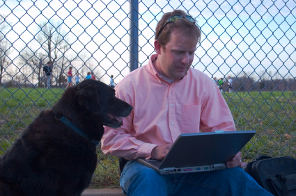 Father at game with laptop and dog