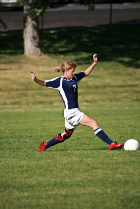 Female soccer player stretching for ball