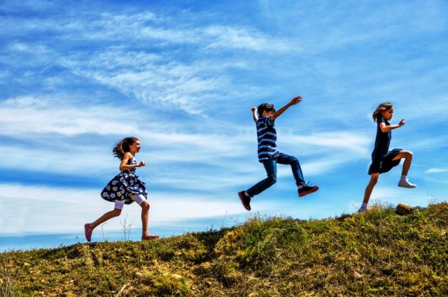 Kids running happily on grassy field