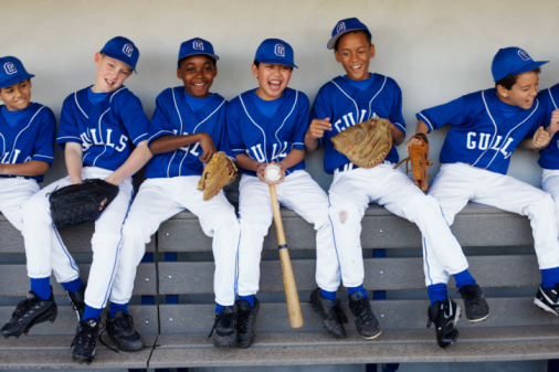 Youth baseball team on bench laughing