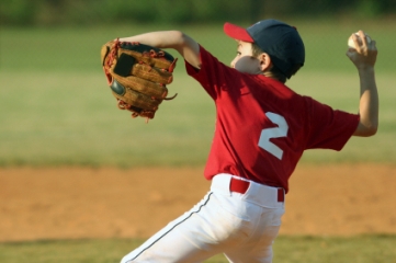 Youth baseball pitcher delivering ball to plate