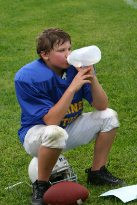 Young football player drinking from water bottle
