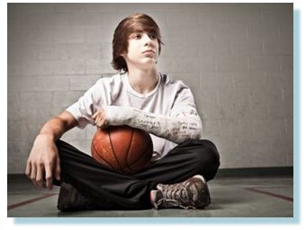 Teenager holding basketball with cast on arm
