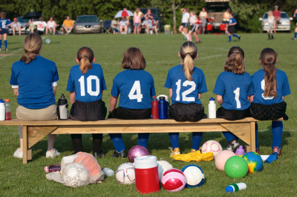 Girl soccer players on bench watching action